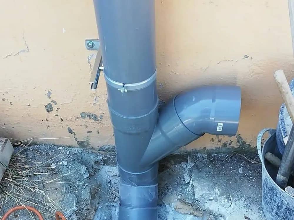Bajante nueva de PVC instalada y conectada en el patio de un edificio