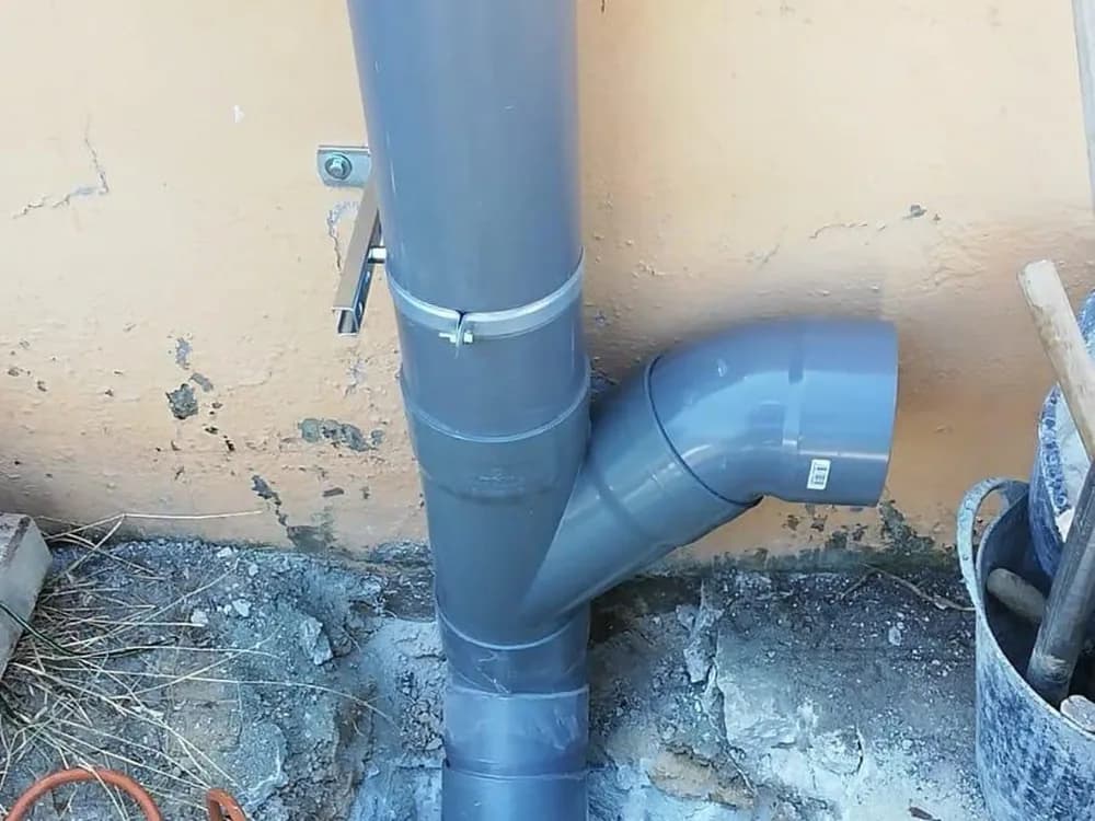 Bajante nueva de PVC instalada y conectada en el patio de un edificio